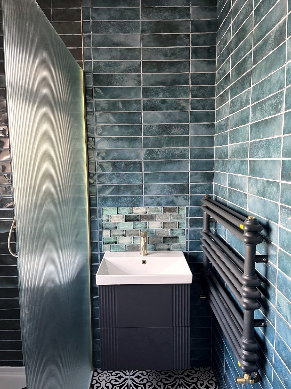 Cloakroom in glazed teal metro tile with fluted vanity and brass tap