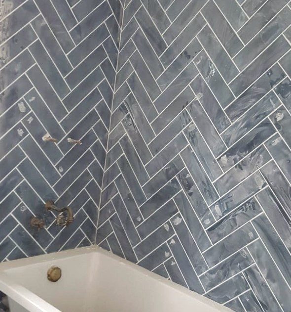 Herringbone tiled bath surround in blue-grey marbled tile